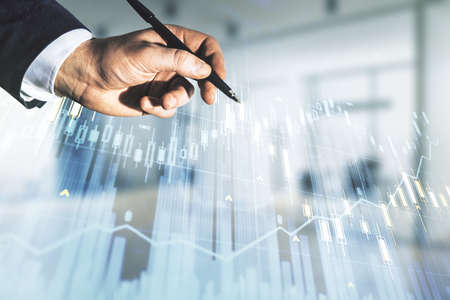 Man hand with pen working with abstract virtual financial graph on blurred office background, forex and investment concept. Multiexposureの写真素材