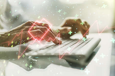 Creative concept of heart pulse illustration and hands typing on laptop on background. Medicine and healthcare concept. Multiexposureの写真素材