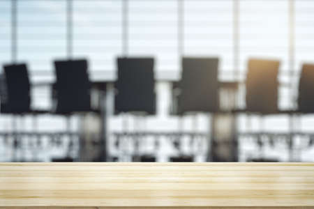 Empty wooden office table with light sunny furnished conference room with large window on background, mockupの写真素材