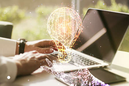 Double exposure of creative light bulb hologram with hands typing on laptop on background, research and development conceptの写真素材