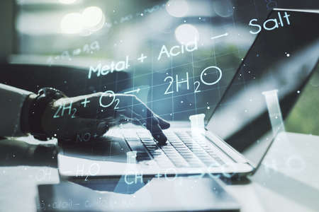 Double exposure of creative chemistry concept with hands typing on laptop on background, research and development conceptの写真素材
