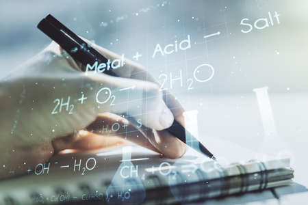 Creative chemistry concept with woman hand writing in notebook on background. Multiexposureの写真素材