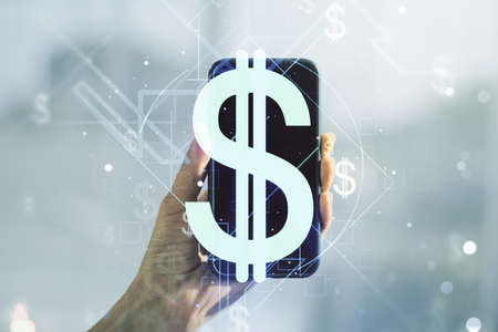 Double exposure of creative USD symbols hologram and hand with cell phone on background. Banking and investing conceptの写真素材