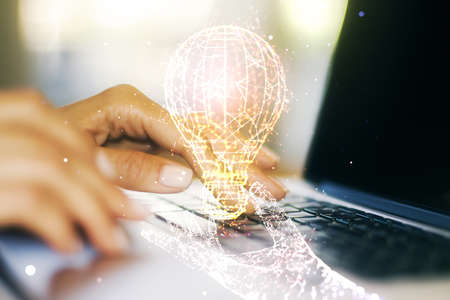 Creative light bulb illustration with hands typing on computer keyboard on background, future technology concept. Multiexposureの写真素材