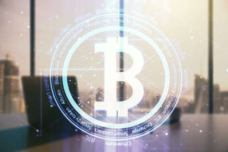 Double exposure of creative Bitcoin symbol hologram and modern desk with computer on background. Mining and blockchain conceptの写真素材