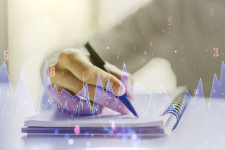 Double exposure of abstract creative statistics data hologram with man hand writing in notepad on background, analytics and forecasting conceptの写真素材