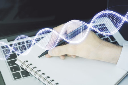 Double exposure of creative DNA hologram and hand writing in notebook on background with laptop. Bio...