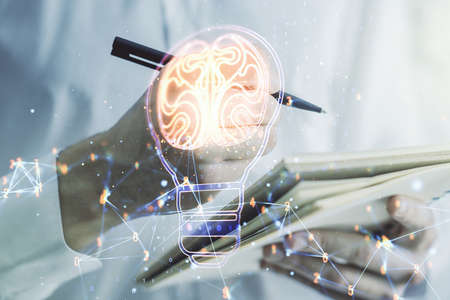 Creative light bulb with human brain hologram and with man hand writing in notepad on background, artificial Intelligence and neural networks concept. Multiexposureの写真素材