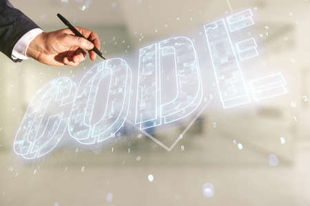 Man hand with pen writes Code word hologram on blurred office background, artificial intelligence and neural networks concept. Multiexposureの写真素材