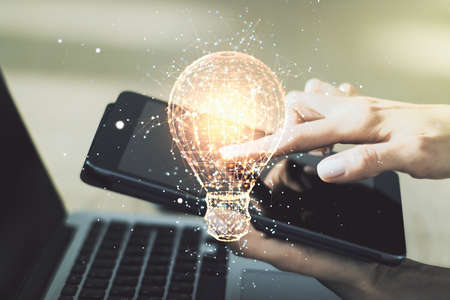 Double exposure of creative light bulb hologram with finger clicks on a digital tablet on background, research and development conceptの写真素材