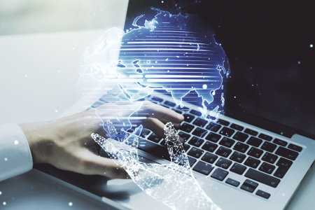 Double exposure of abstract digital world map and hand typing on laptop on background, research and...