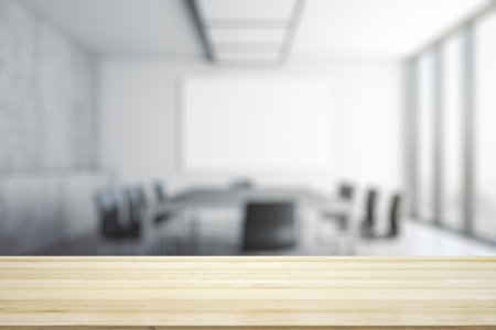 Blank wooden office desk with light furnished meeting room with big window on background, mockup