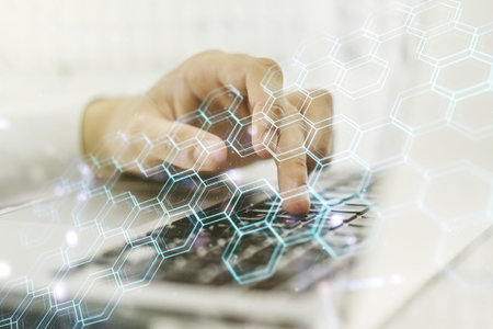 Creative concept of wireless technology with hexagon hologram and hands typing on laptop on...
