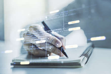 Double exposure of abstract programming language with man hand writing in notebook on background, research and development conceptの写真素材