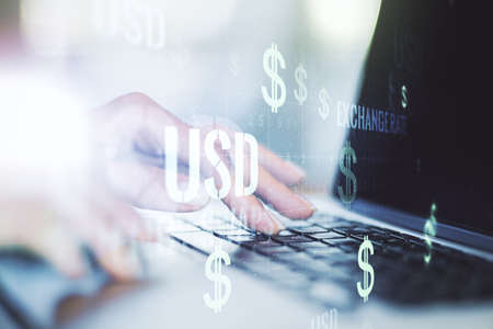Double exposure of creative USD symbols hologram and hands typing on laptop on background. Banking and investing conceptの写真素材
