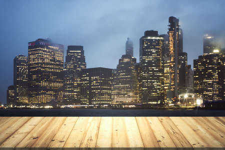 Wooden tabletop with beautiful Manhattan skyscrapers at evening on background, mock upの写真素材