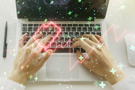 Creative abstract heart pulse hologram and hands typing on computer keyboard on background, online...