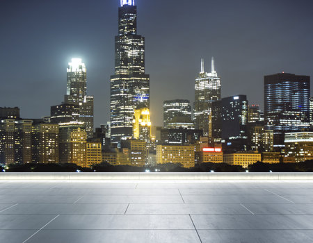 Empty concrete rooftop on the background of a beautiful blurry Chicago city skyline at twilight,...