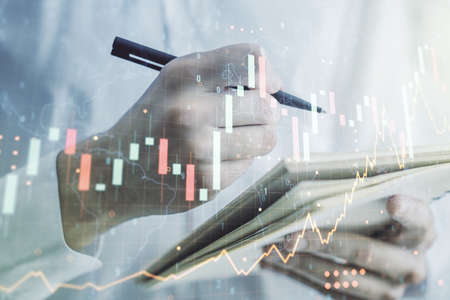 Multi exposure of abstract creative financial graph with world map and with man hand writing in notebook on background, forex and investment conceptの写真素材