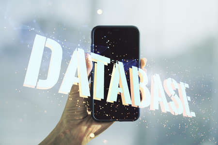 Double exposure of creative Database word hologram and hand with cell phone on background, research and development conceptの写真素材
