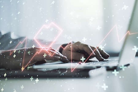 Creative abstract heart pulse hologram and hands typing on computer keyboard on background, online medical consulting concept. Multiexposureの写真素材