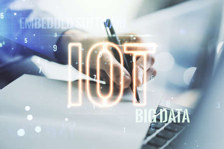 Creative IOT hologram with hand writing in notepad on background with laptop, internet of things concept. Multiexposureの写真素材