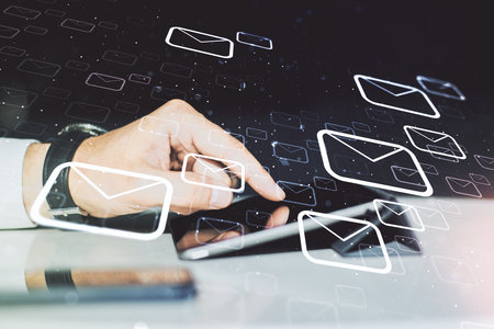 Double exposure of postal envelopes hologram with finger clicks on a digital tablet on background. Electronic mail and spam conceptの写真素材