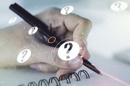 Creative abstract question mark hologram and man hand writing in diary on background, future technology concept. Multi exposureの写真素材