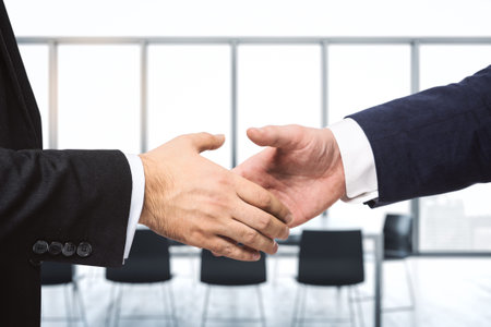 Handshake of two businessmen on the background of bright conference room, partnership concept, close upの写真素材