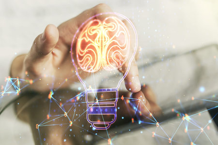 Creative light bulb illustration with human brain and with finger presses on a digital tablet on...