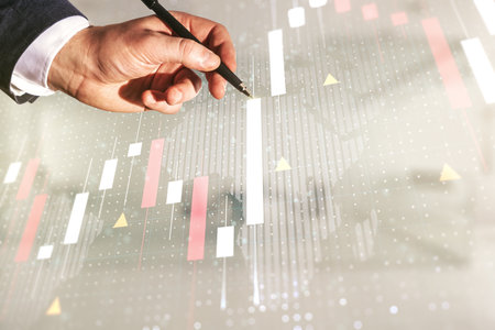 Multi exposure of businessman hand with pen working with virtual creative financial graph and world map on blurred office background, forex and investment conceptの写真素材