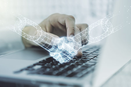 Creative concept of blockchain technology with handshake and hands typing on laptop on background....