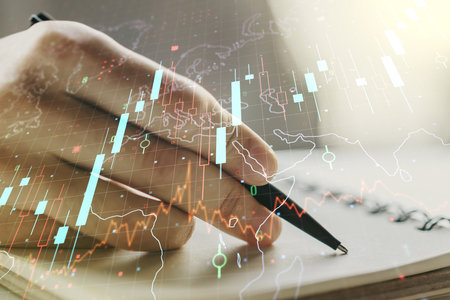 Double exposure of abstract creative financial chart with world map and with man hand writing in notebook on background, research and strategy conceptの写真素材