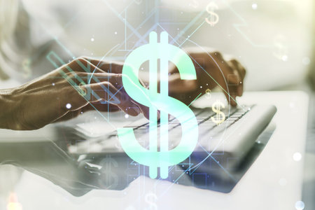 Double exposure of creative USD symbols hologram and hands typing on laptop on background. Banking...