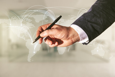 Double exposure of man hand with pen working with abstract digital world map hologram with connections on blurred office background, research and strategy conceptの写真素材