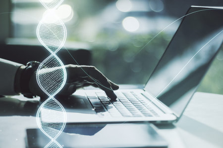 Double exposure of creative DNA hologram and hands typing on laptop on background. Bio Engineering...