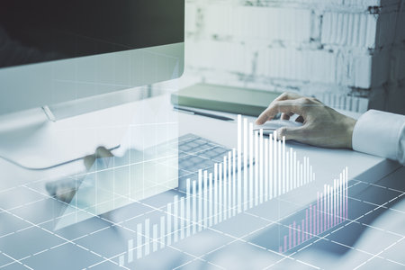 Abstract creative financial graph with hand typing on laptop on background, financial and trading concept. Multiexposureの写真素材