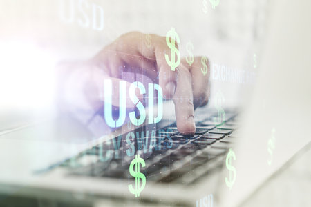 Creative concept of USD symbols illustration and hands typing on laptop on background. Trading and currency concept. Multiexposureの写真素材