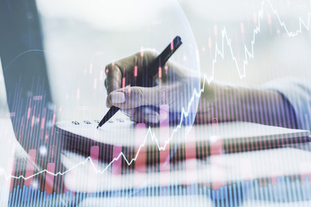Multi exposure of abstract financial graph with world map and with hand writing in diary on background with laptop, financial and trading conceptの写真素材