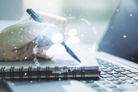 Double exposure of people icons hologram and hand writing in notebook on background with laptop....