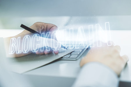 Creative abstract blockchain technology hologram and hand writing in diary on background with...