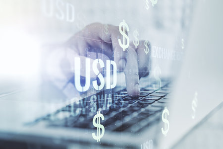 Double exposure of creative USD symbols hologram and hands typing on laptop on background. Banking and investing conceptの写真素材
