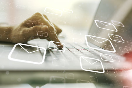 Double exposure of postal envelopes hologram with hands typing on laptop on background. Electronic mail and spam conceptの写真素材