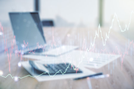 Double exposure of abstract creative financial chart hologram on blurry calculator with laptop background, research and strategy conceptの写真素材