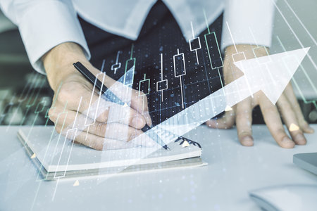 Multi exposure of abstract financial diagram with upward arrow and hand writing in notepad on background with laptop, rise and breakthrough conceptの写真素材