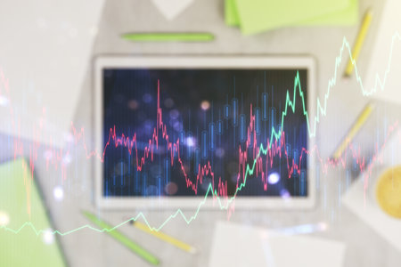 Multi exposure of abstract financial graph and modern digital tablet on desktop on background, top view, financial and trading conceptの写真素材