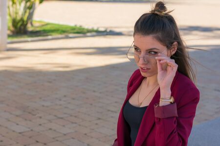 Attractive girl with red jacket and glasses in a parkの写真素材