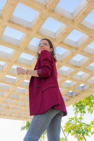 Young and cheerful woman in contrapicado view under a roof of concrete boxes open to the sky in a parkの写真素材