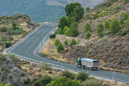 Tipper truck driving on a secondary road and uphill.の写真素材