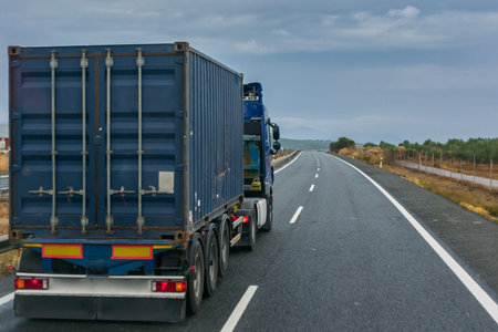 Blue container truck driving on the highway on a cloudy day.
